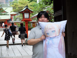 人在日本神社手持動漫枕頭，背景有紅色燈籠和綠樹。 — Xxxtentacion 動畫 GIF 壁紙