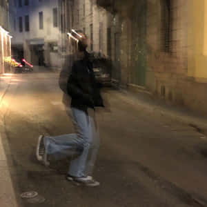 夜晚在昏暗的城市街道上行走的人，帶有動態模糊效果。 — Running 壁紙