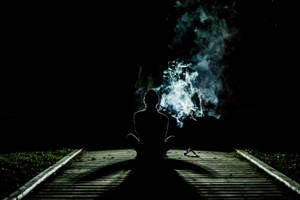 夜間在木徑上冥想的人，背後有發光的煙霧。 — 抽菸 壁紙