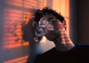 一個人在溫暖的橙色光線中呼出煙霧，牆上有條紋陰影。 — 煙動圖 壁紙