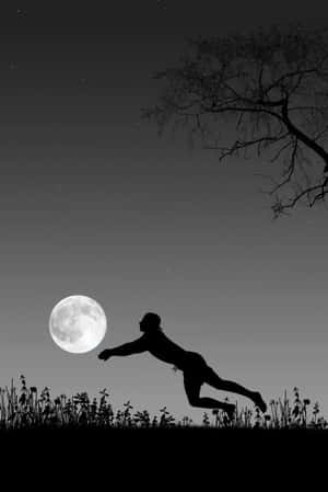 一個人在滿天星斗的夜空下，伴隨著光禿的樹枝向月亮躍起。 — 排球 壁紙