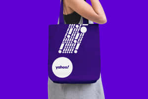 人拿著帶有白色標誌和幾何設計的紫色 Yahoo 手提袋。 — 雅虎 壁紙