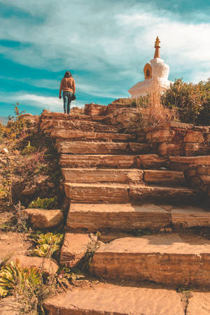 在藍天下，一個人沿著石階爬向山上的白色佛塔。 — 不丹 壁紙