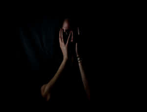 黑暗中用手遮臉只露出一隻眼睛的人。 — 簡約暗黑美學 壁紙