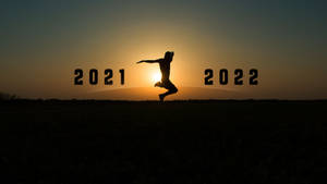 日落時分，一個人在2021年和2022年之間跳躍的剪影。 — 新年快樂 2020 壁紙