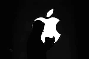 夜晚在發光Apple標誌前手持電話的人。 — 蘋果 壁紙