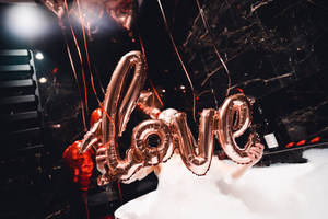 在泡泡浴中拿著玫瑰金色 love 氣球的人，有紅色氣球和彩帶。 — 熱氣球 壁紙