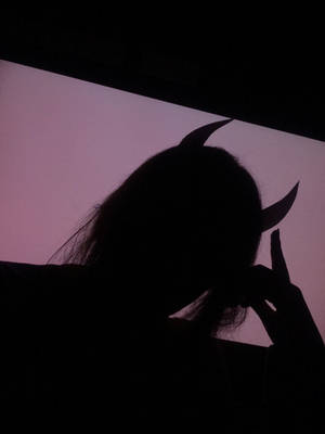 一個人戴著惡魔角在黃昏時做出和平手勢的剪影。 — 惡魔角 壁紙