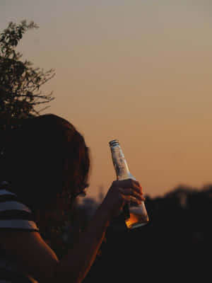 日落時手持啤酒瓶的人與樹木剪影 — 獨自一人 壁紙