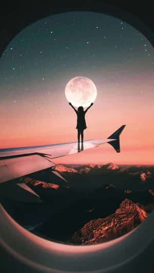 人站在飛機機翼上伸手觸摸山上的月亮 — 月光 壁紙