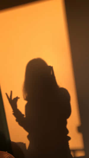 一個人的剪影對著發光的窗戶做出和平手勢。 — 暗黑少女風 壁紙