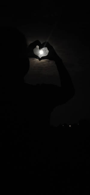 夜晚一個人用雙手在月亮周圍做出心形的剪影。 — 簡約暗黑美學 壁紙