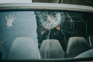 手按壓在破裂的車窗上，顯示損壞和反射。 — 碎裂 壁紙