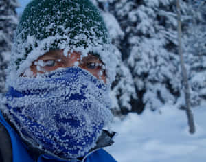 臉上結霜、戴著護目鏡的人，身處雪地森林中 — 寒冷 壁紙