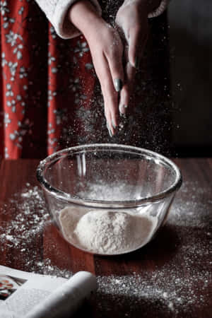 雙手在木桌上的玻璃碗中撒麵粉。 — 小米平板 7S Pro 12.5 壁紙