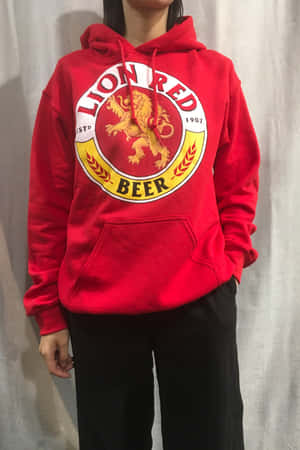 穿著帶有金色獅子標誌的紅色Lion Red Beer連帽衫的人。 — Vivo Pad 壁紙