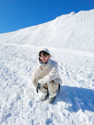 穿著冬季服裝的人蹲在深雪中，頭頂是晴朗的藍天。 — 酷寒冬季 壁紙