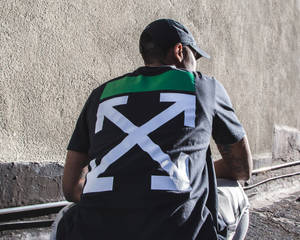穿著品牌T恤的人靠著混凝土牆坐著 — Off white 標誌 壁紙