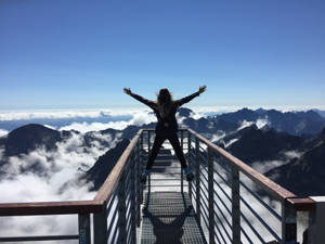 人在山頂觀景台張開雙臂，俯瞰雲海。 — 假期 壁紙