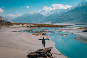 人站在岩石上張開雙臂俯瞰山間河流 — 丘陵景觀 壁紙