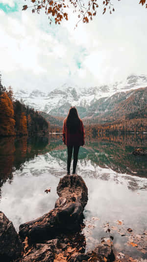 秋天湖邊木頭上的人，倒映著山景。 — 獨自一人 壁紙
