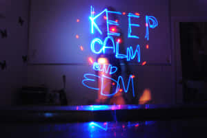 霓虹燈牌寫著 KEEP CALM AND EDM，在昏暗的房間裡發光，牆上有蝴蝶貼紙。 — MacBook Pro M3 壁紙