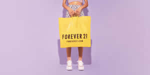 一個人手持黃色Forever 21購物袋，背景為紫色。 — 永遠21 壁紙