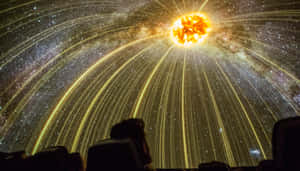 觀眾剪影觀看在弧形圓頂天花板上的星爆投影。 — 夜空 壁紙