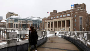 冬天，一個人在雪橋上走向大學建築。