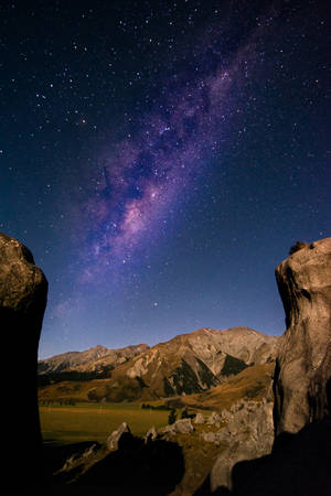 銀河系在夜間山脈上方發光，由岩石框住 — 岩石 壁紙