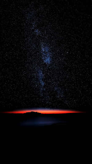 星空之夜，銀河在紅色光芒的地平線上。
