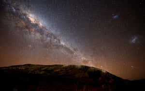 銀河系在星空下拱起於黑暗的山影之上。 — 星星 壁紙