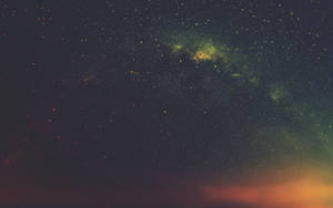 廣闊的夜空，星星和彩色星雲在地平線上方發光。 — 桌面 壁紙
