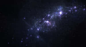 一個充滿活力的宇宙場景，閃爍的藍色星星和旋轉的星雲在深空中。 — 在我們之中 太空 壁紙