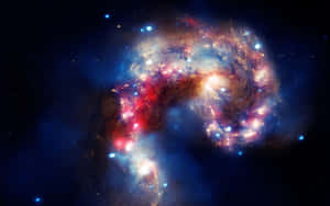 一個色彩繽紛的螺旋星系，在黑暗的星空中散發著紅色、藍色和金色的光芒。 — 宇宙 壁紙