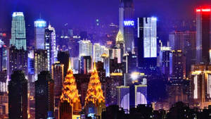 一個充滿活力的夜景城市，燈火通明的摩天大樓閃爍著藍色、紫色和金色。 — 夜景城市 壁紙