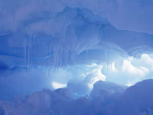 一個帶有冰柱和積雪覆蓋開口的藍色冰洞。 — 火焰與冰 壁紙