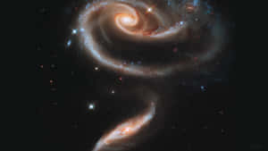兩個螺旋星系在星光閃爍的黑色天空中進行宇宙碰撞之舞。 — 星星 壁紙