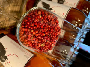 一個裝滿紅胡椒粒的玻璃杯放在有標籤的瓶子上。 — 粉紅閃光 壁紙