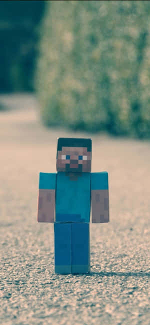 像素化Minecraft Steve公仔站在室外碎石上。 — Galaxy S25 Edge 壁紙