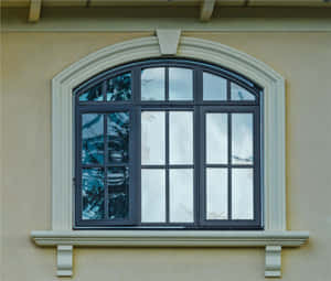 拱形窗戶，深色框架，在米色灰泥建築中反射雲朵和樹木。 — Windows 壁紙