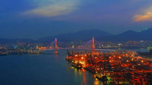 港口上照明橋樑的夜景，有貨運集裝箱和城市燈光。 — 釜山 壁紙