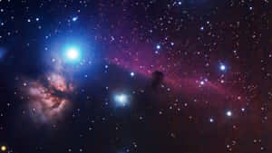 在深空中無數星辰間閃耀的鮮豔藍色和洋紅色星雲。 — 宇宙 壁紙
