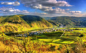 葡萄園和河谷，小鎮坐落在日落時分起伏的丘陵之間。 — 山景 壁紙