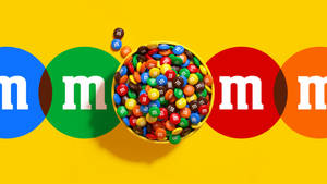 一碗色彩繽紛的M&M's糖果，周圍環繞著品牌標誌圓圈。 — 巧克力 壁紙