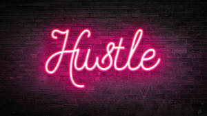 粉紅色霓虹燈牌在深色磚牆上顯示Hustle。