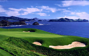 沿海高爾夫球場，享有海景和連綿起伏的綠色山丘，天空晴朗。 — 16:10 壁紙