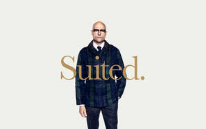 一個光頭戴眼鏡及格紋外套的男人，金色顯示「Suited.」字樣。