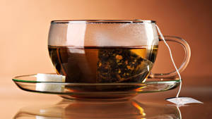 一個玻璃茶杯，內有茶包和方糖，放在茶托上。 — 茶 壁紙