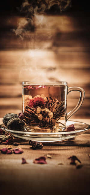 木桌上玻璃杯中的冒煙花草茶與乾燥花 — Galaxy S26 壁紙